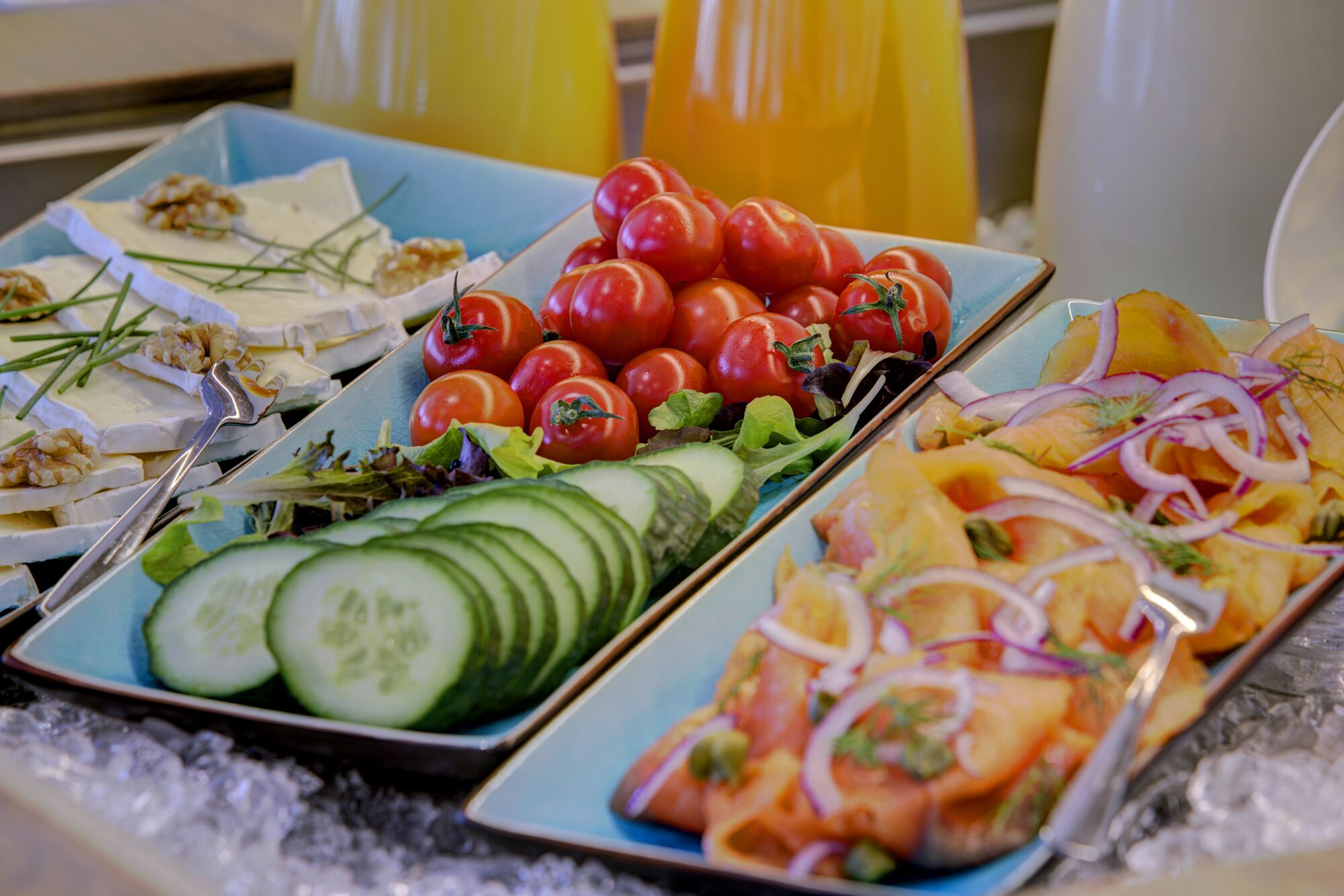 A buffet with various food items including tomatoes, cucumbers, and sliced onions.