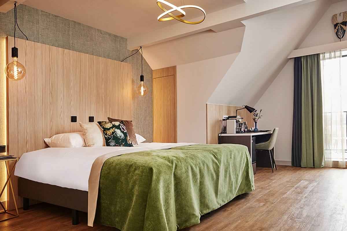 Un dormitorio moderno con cama, escritorio y lámpara.