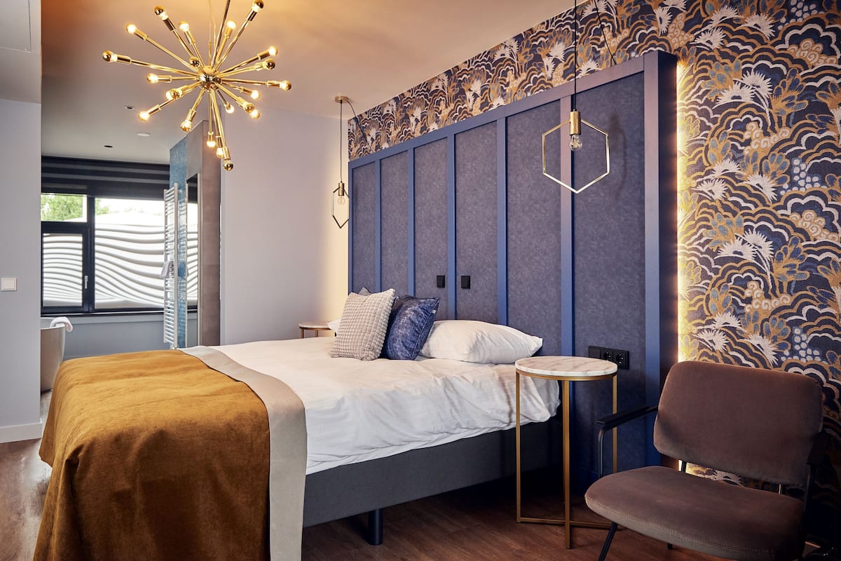 Un dormitorio moderno con cama, mesita de noche, silla y paneles decorativos en la pared.