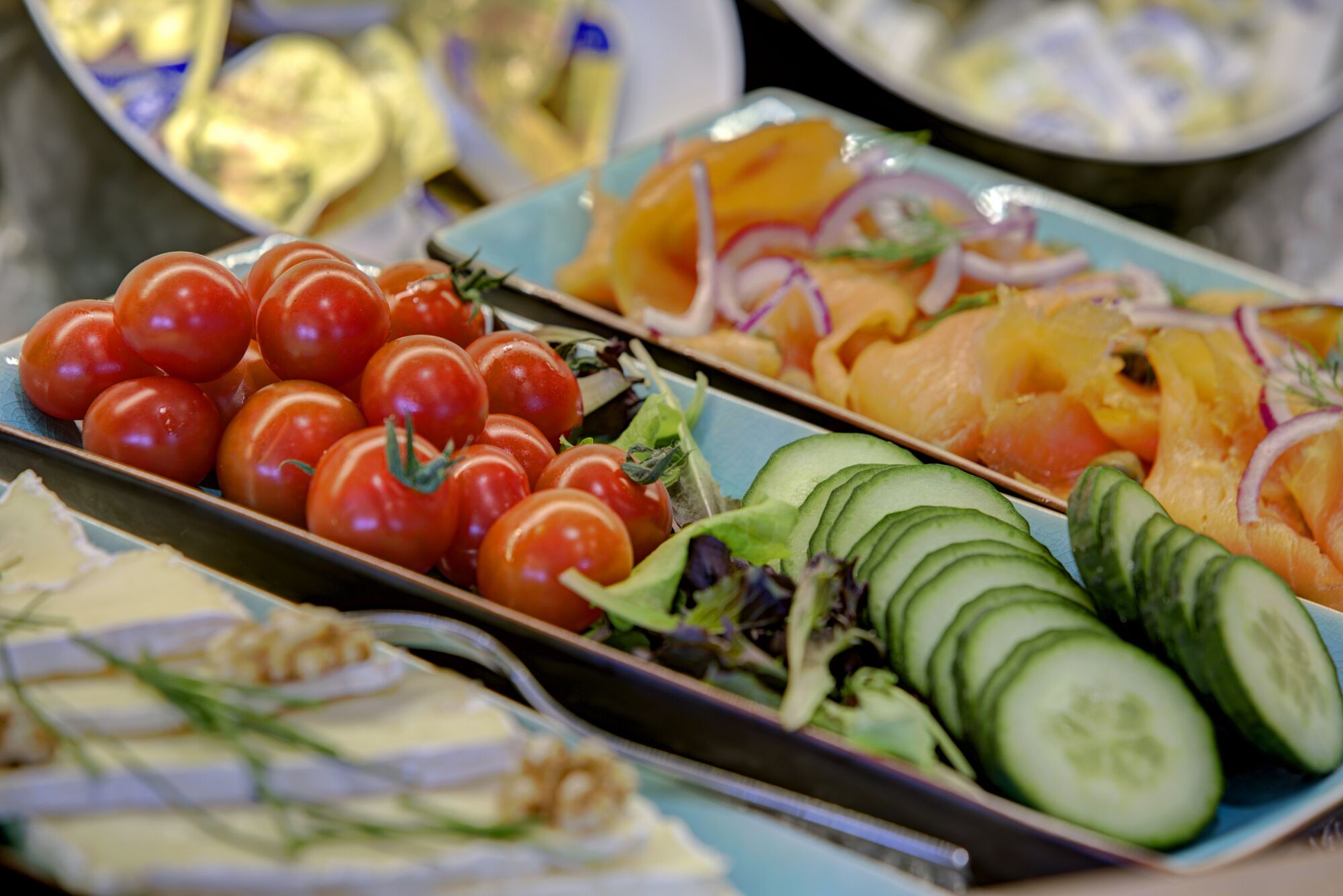 A variety of food items including tomatoes, cucumbers, and sliced oranges on a tray.