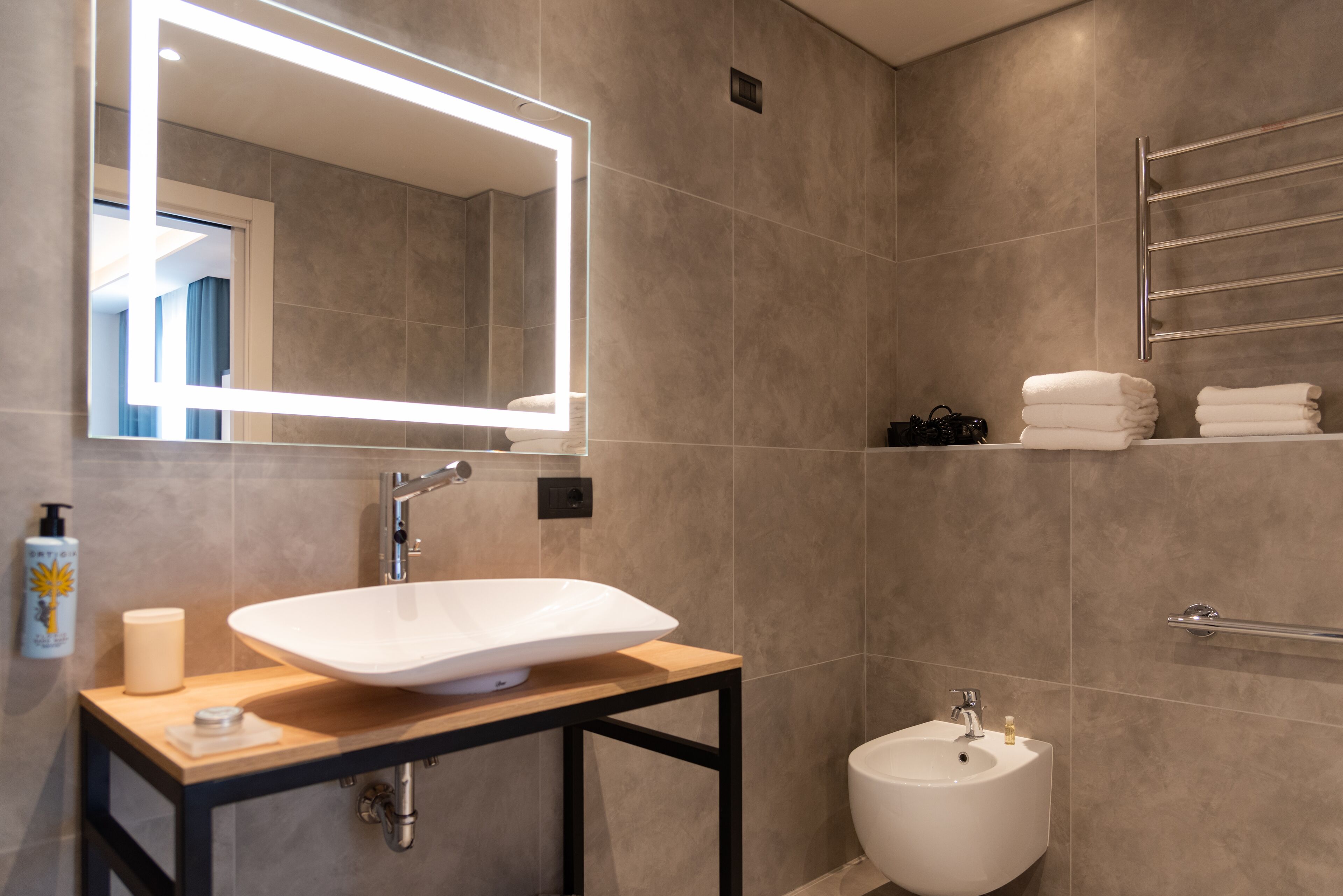 Un baño moderno con un espejo grande, un lavabo sobre encimera, un bidé y un perchero para toallas.