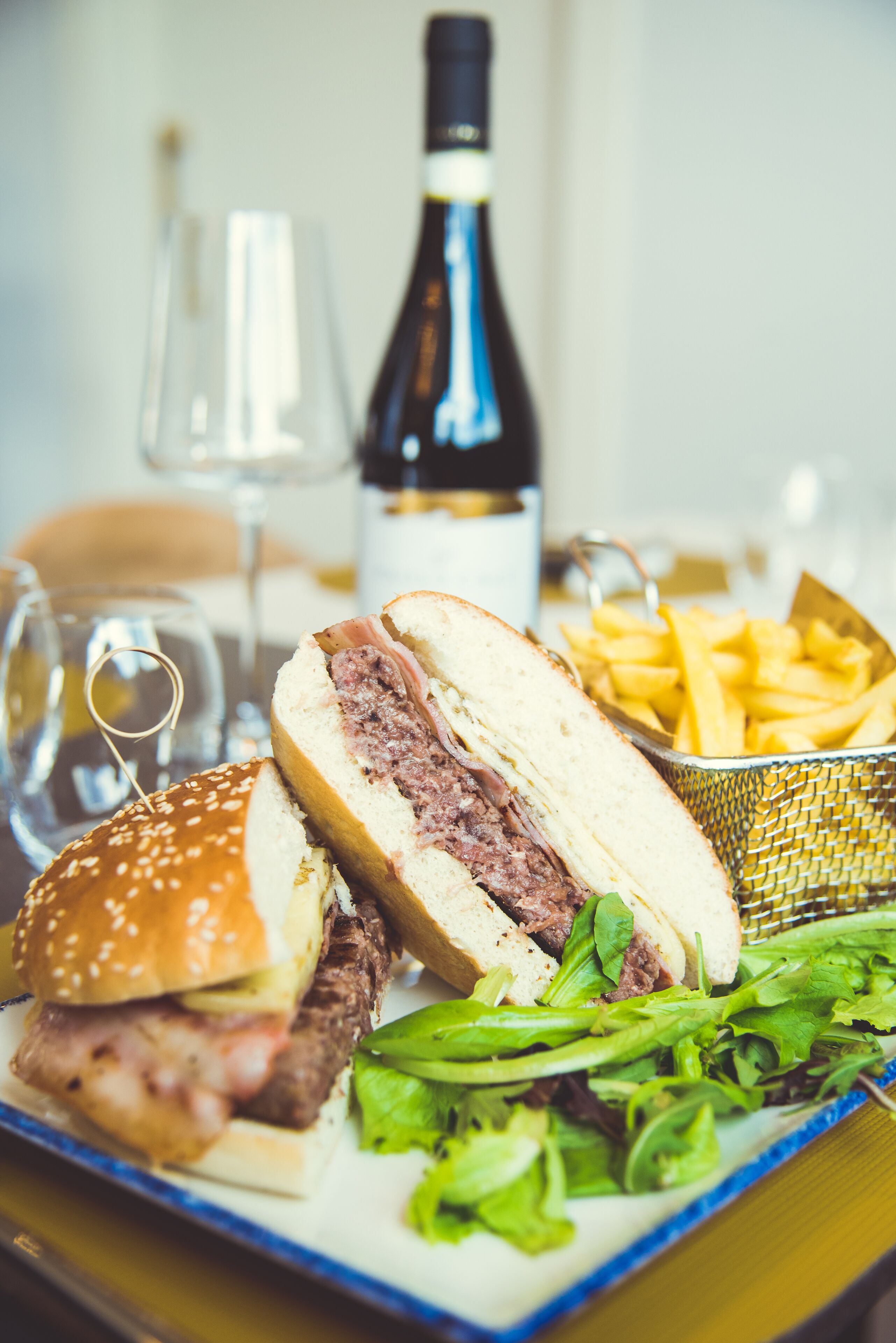 Un repas composé d’un sandwich, de frites et d’une bouteille de vin, le tout servi sur une table.