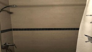 Un bagno con doccia, un portasciugamani e pavimento piastrellato.