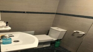 A small bathroom with a white sink, toilet, and a green bottle on the floor. - Furnished apartment in Marrakech EN 26 (Marrakech)