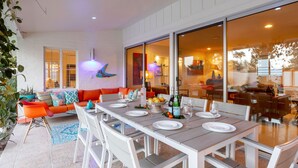 A dining area with a long table set for six, surrounded by white chairs. - Palm Springs Trousdale – Iconic Midcentury Retreat (Palm Springs)