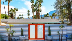 A building with a red door, palm trees, and cacti in front. - Palm Springs Trousdale – Iconic Midcentury Retreat (Palm Springs)
