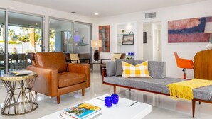 A modern living room with a sofa, armchairs, a coffee table, and a glass door leading to a balcony. - Palm Springs Trousdale – Iconic Midcentury Retreat (Palm Springs)