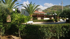 A residential area with a house, palm trees, and a hill in the background. - Relaxing Apartment for 2 People in Residence (Cefalù)