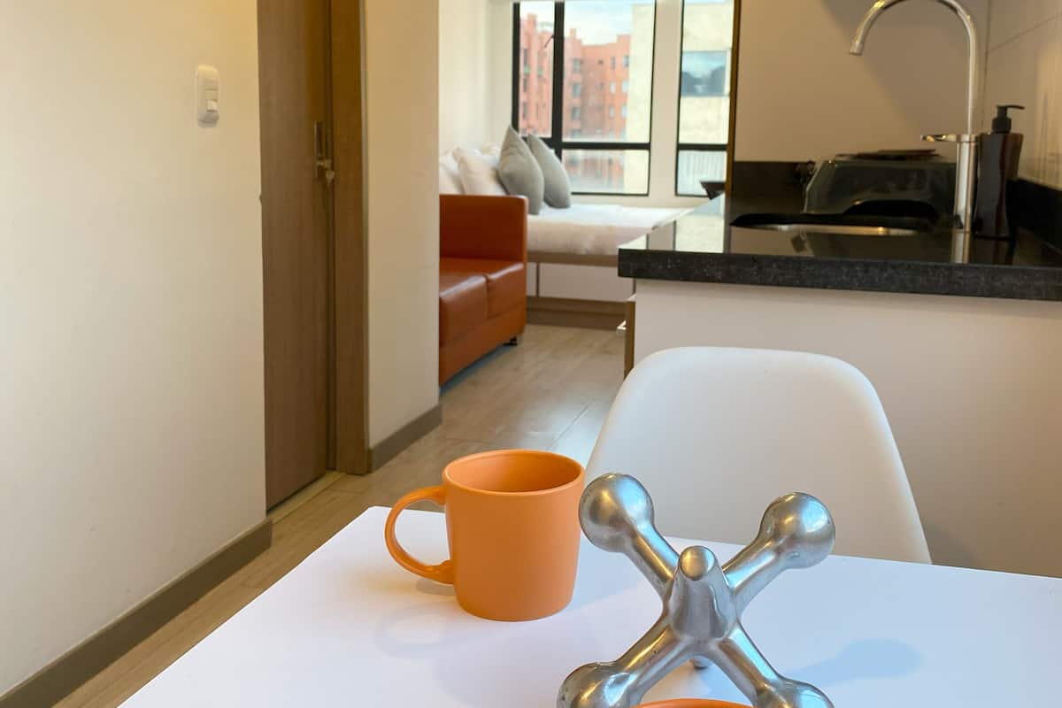 A modern kitchen with a white countertop, two orange mugs, and a silver faucet.