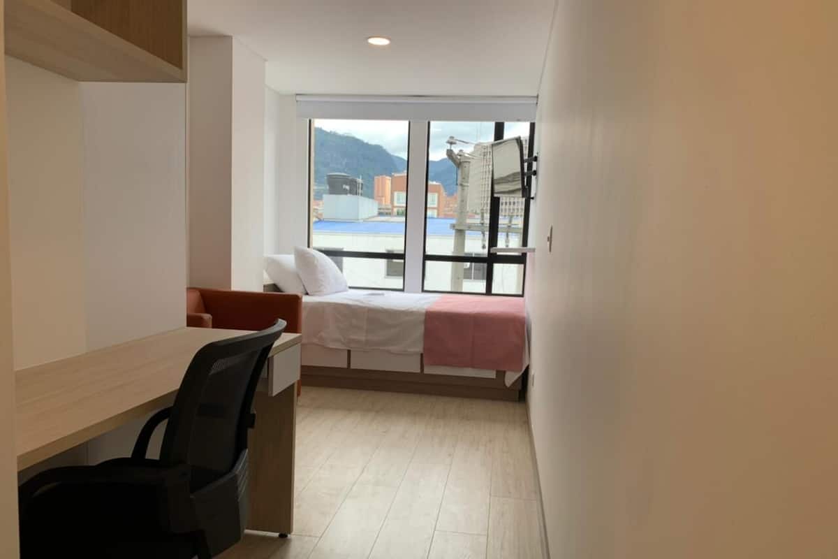 A bedroom with a bed, a desk, and a chair.