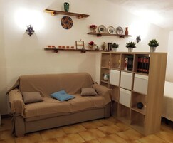 Una sala de estar acogedora con un sofá color beige, una estantería de madera y platos decorativos en la pared.