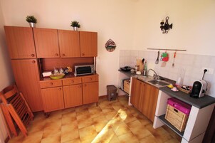 A compact kitchen with wooden cabinets, a microwave, a sink, and various kitchen utensils.