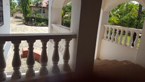 Een balkon met witte balustrades, met uitzicht op een tuin en een huis.