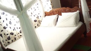 Een bed met hemel, gordijnen met bloemenprint en een houten hoofdbord.