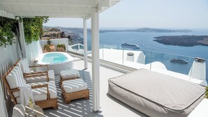 A terrace with a hot tub, lounge chairs, and a view of the sea. - Native Eco Villas (Santorini)
