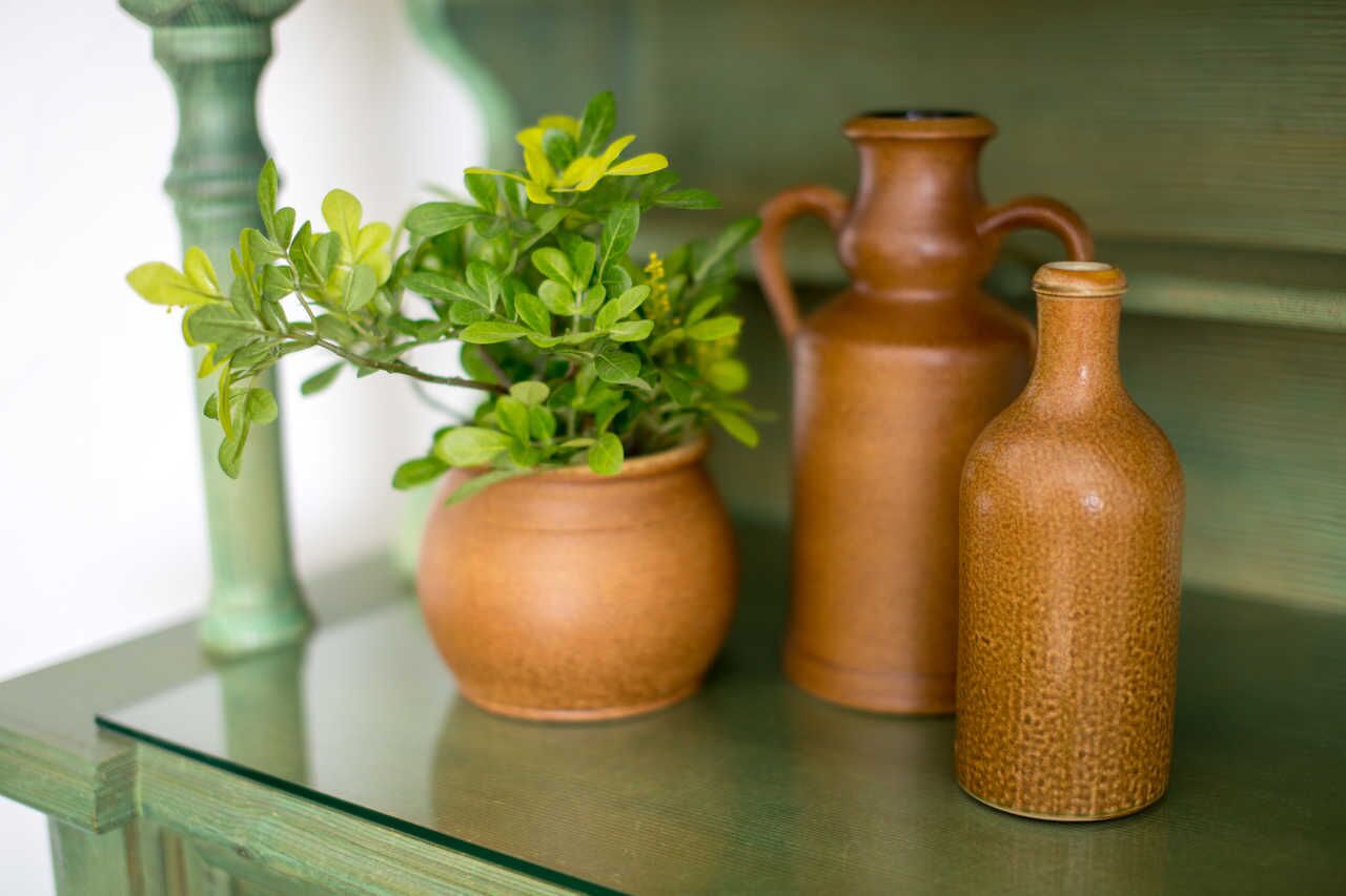 A green glass table with a potted plant and two ceramic vases.