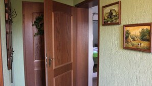 Une porte en bois avec une poignée en laiton, un mur vert et deux tableaux encadrés.