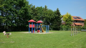A playground with a climbing structure, a slide, and a swing set. - Vacation house Langeoog, Baumann - Vacation house Baumann (Esens)