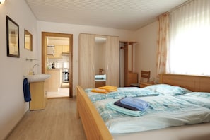 A bedroom with a bed, a bedside table, a wardrobe, and a bathroom with a sink.