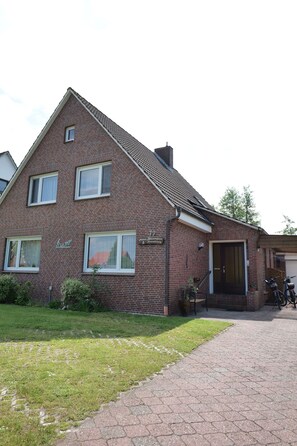 A two-story brick house with a paved driveway and a motorcycle parked outside.