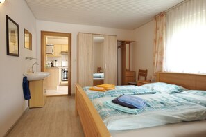 Ein Schlafzimmer mit Bett, Nachttisch, Kleiderschrank und einem Badezimmer mit Waschbecken.
