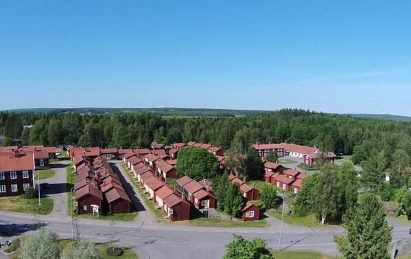 A residential area with red-roofed houses arranged in rows, surrounded by greenery and a clear sky. - Lövångergården (Lövånger)