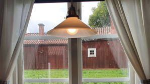 A window with a view of a red barn and green grass. - Lövångergården (Lövånger)