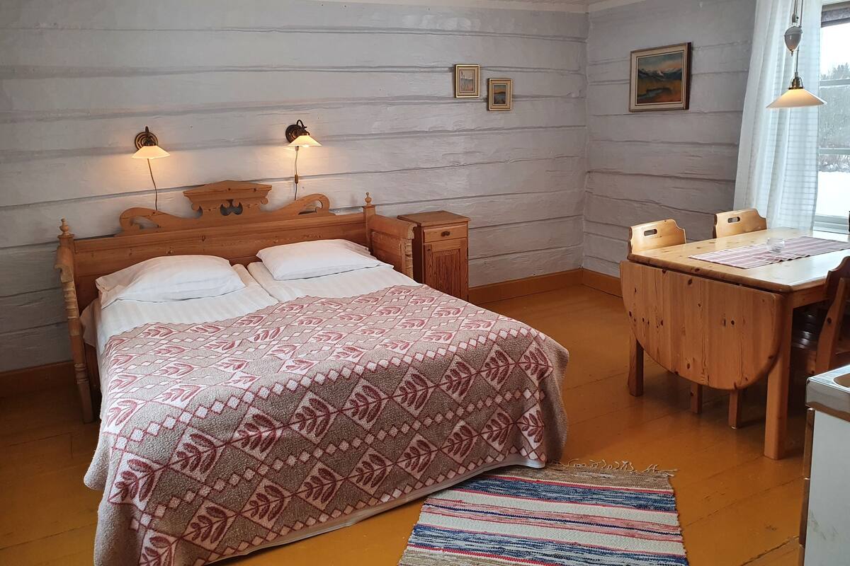 A bedroom with a wooden bed, bedside tables, a wooden desk, and a window with curtains.
