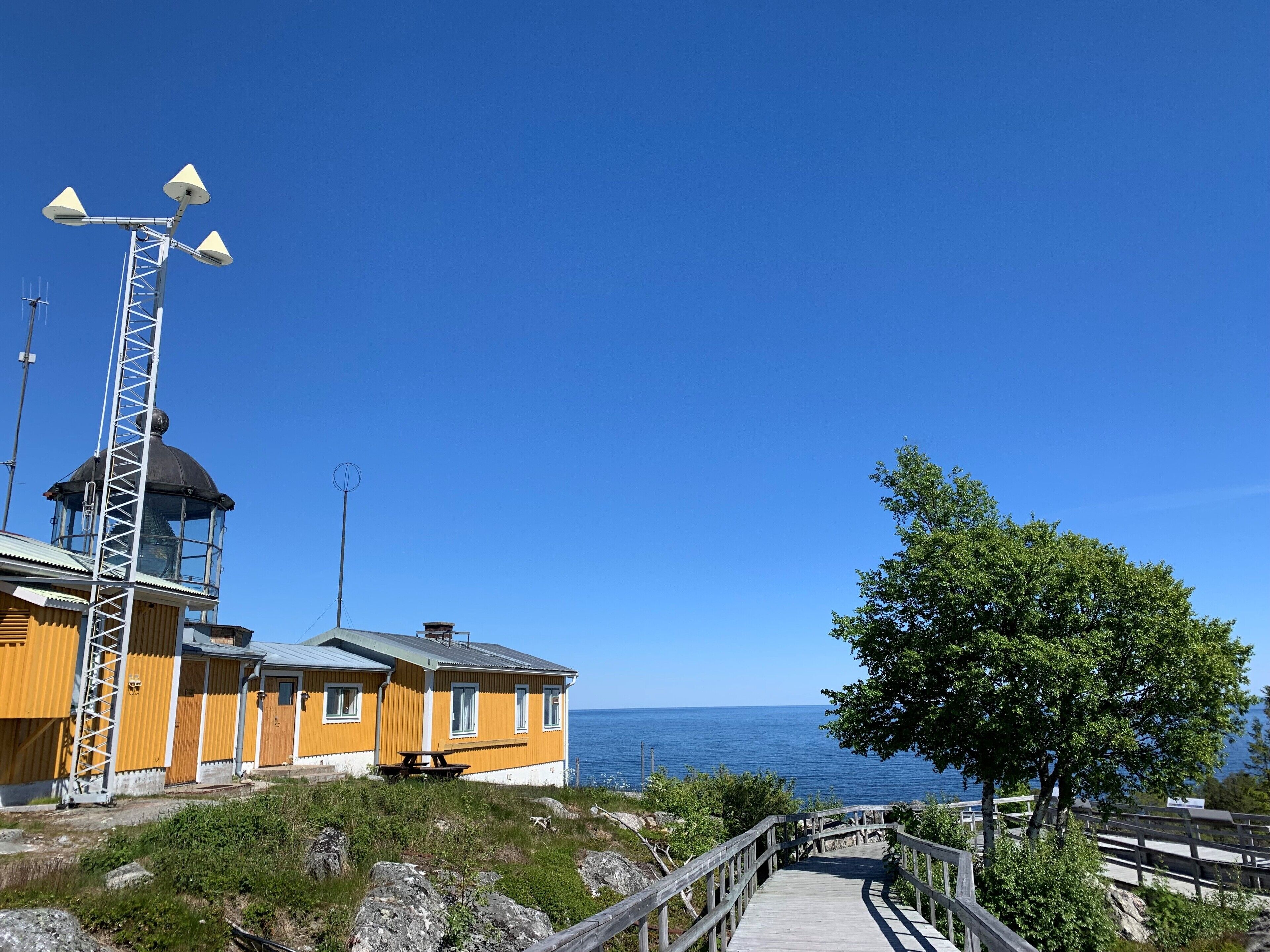 A coastal building with a lighthouse structure, a wooden deck, and a view of the sea.