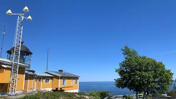 A coastal building with a lighthouse structure, a wooden deck, and a view of the sea.