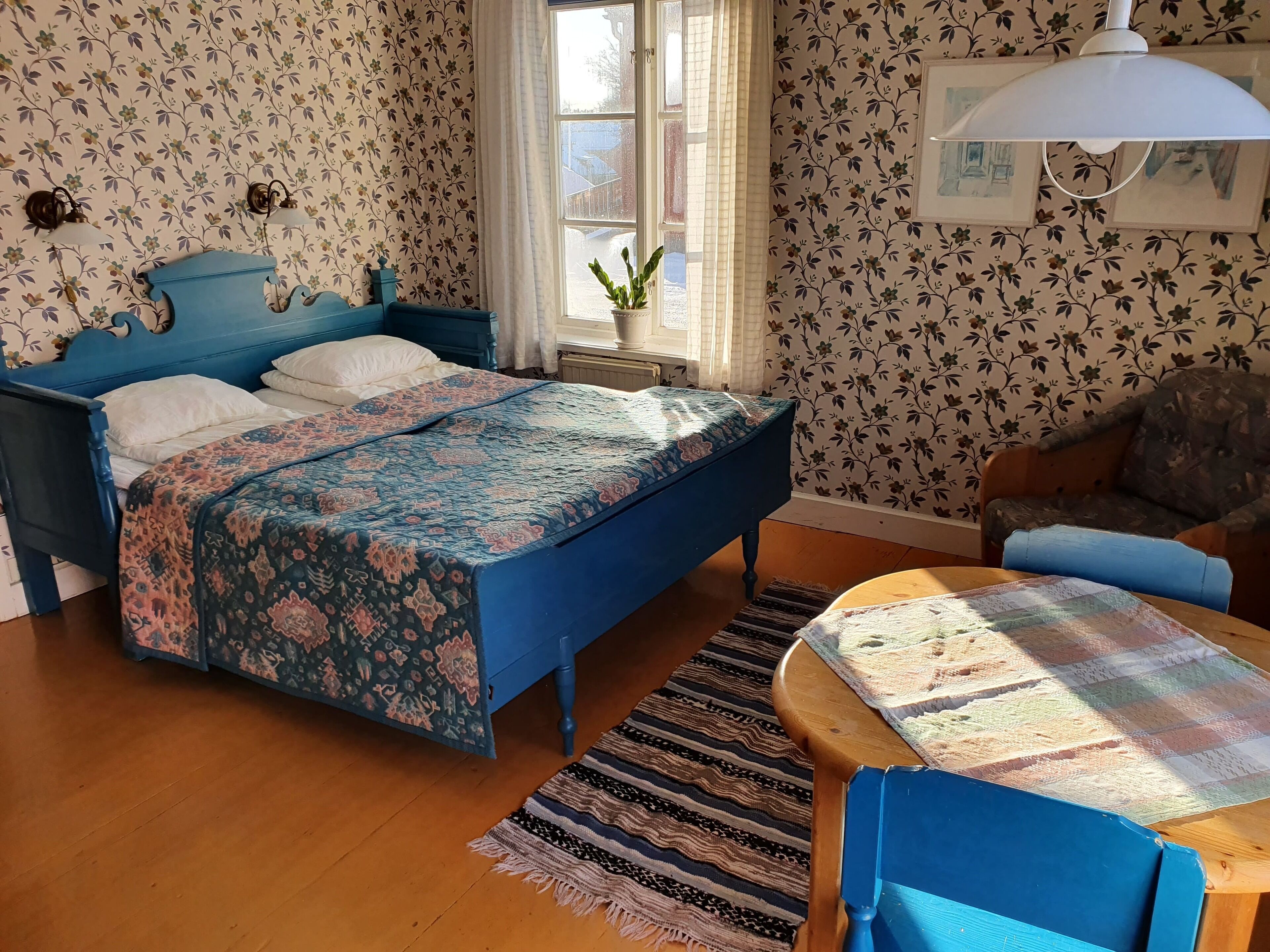 A bedroom with a bed, a chair, a table, and a window.