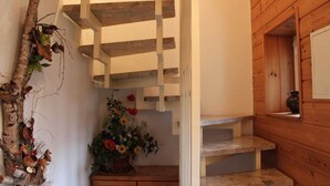 Una escalera de madera con barandilla blanca, un banco de madera y un florero a la derecha.