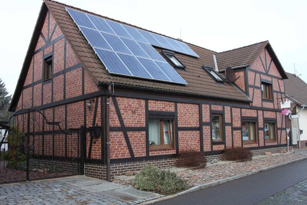 A traditional half-timbered house with solar panels on the roof.