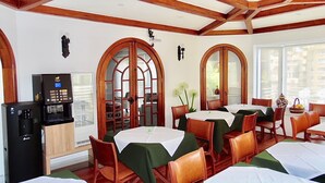 A dining area with wooden beams, arched windows, and tables set with white tablecloths. - Hotel Torreviña (Vina del Mar)