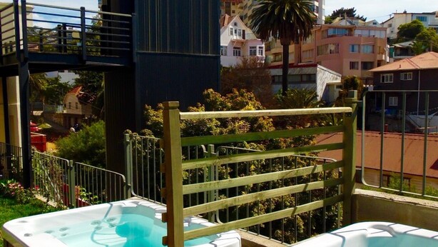A rooftop with two hot tubs, a wooden deck, and a view of surrounding buildings. - Hotel Torreviña (Vina del Mar)