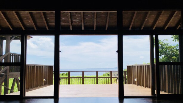 Amplia habitación con una gran terraza de madera que da a un balcón con vistas al mar.