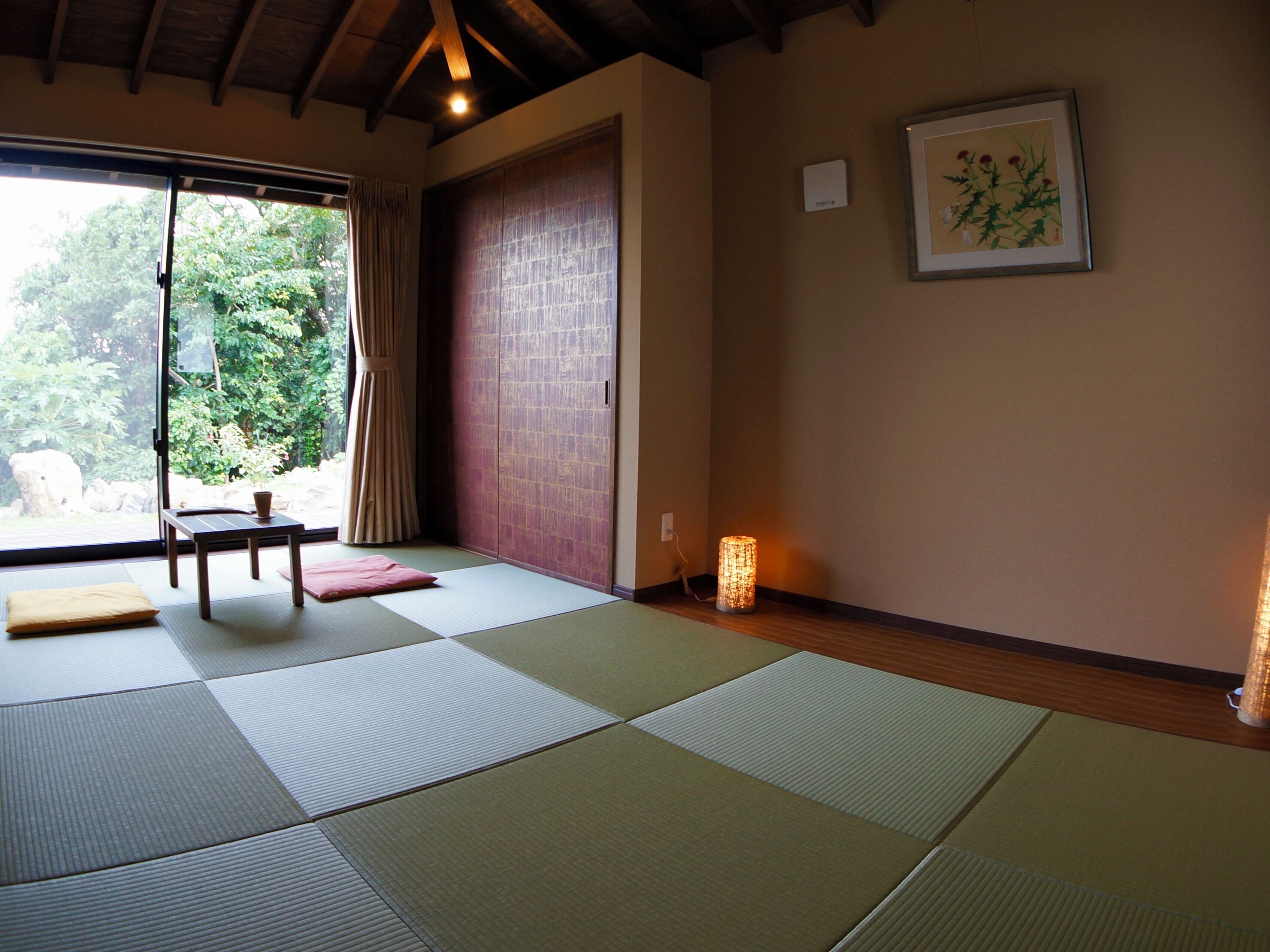 A tatami mat room with a sliding door, a small table, and a framed botanical print on the wall.