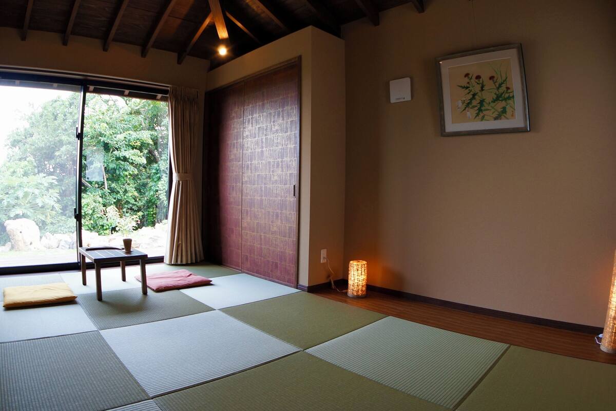 A tatami mat room with a sliding door, a small table, and a framed botanical print on the wall.
