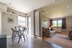 Un salon moderne comprenant un canapé, une table basse et un coin repas avec des chaises.