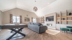 A modern living room with a pool table, a sofa, a TV, and a bookshelf. - The Penthouse @ Carus Green (Kendal)