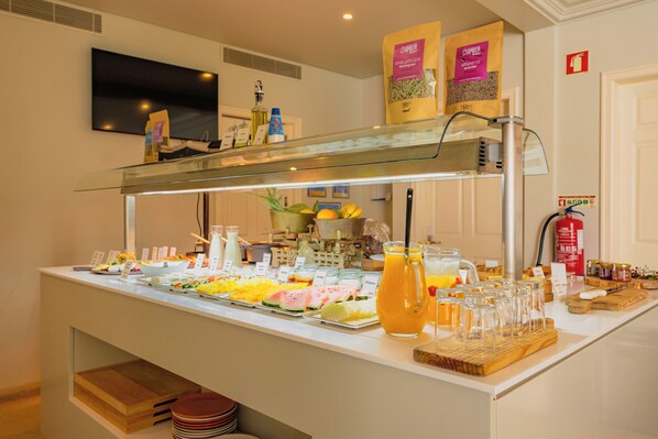 A buffet with various food items and beverages, including a pitcher of orange juice and several glassware items. - Jardim da Lapa by Shiadu (Lisbon)