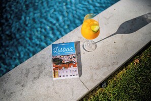 A brochure titled "Lisboa" on a stone ledge by a pool. - Jardim da Lapa by Shiadu (Lisbon)