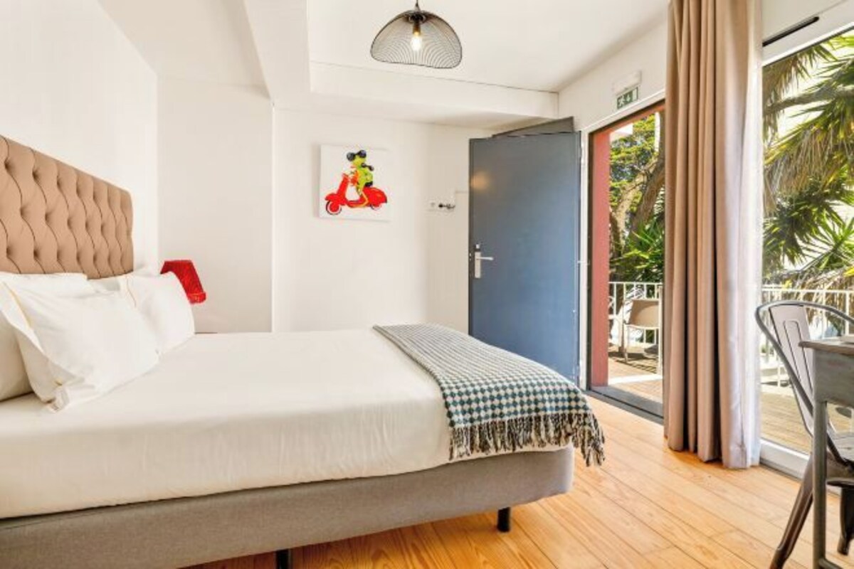 A hotel room with a bed, a door to the balcony, and a view of the outdoors.