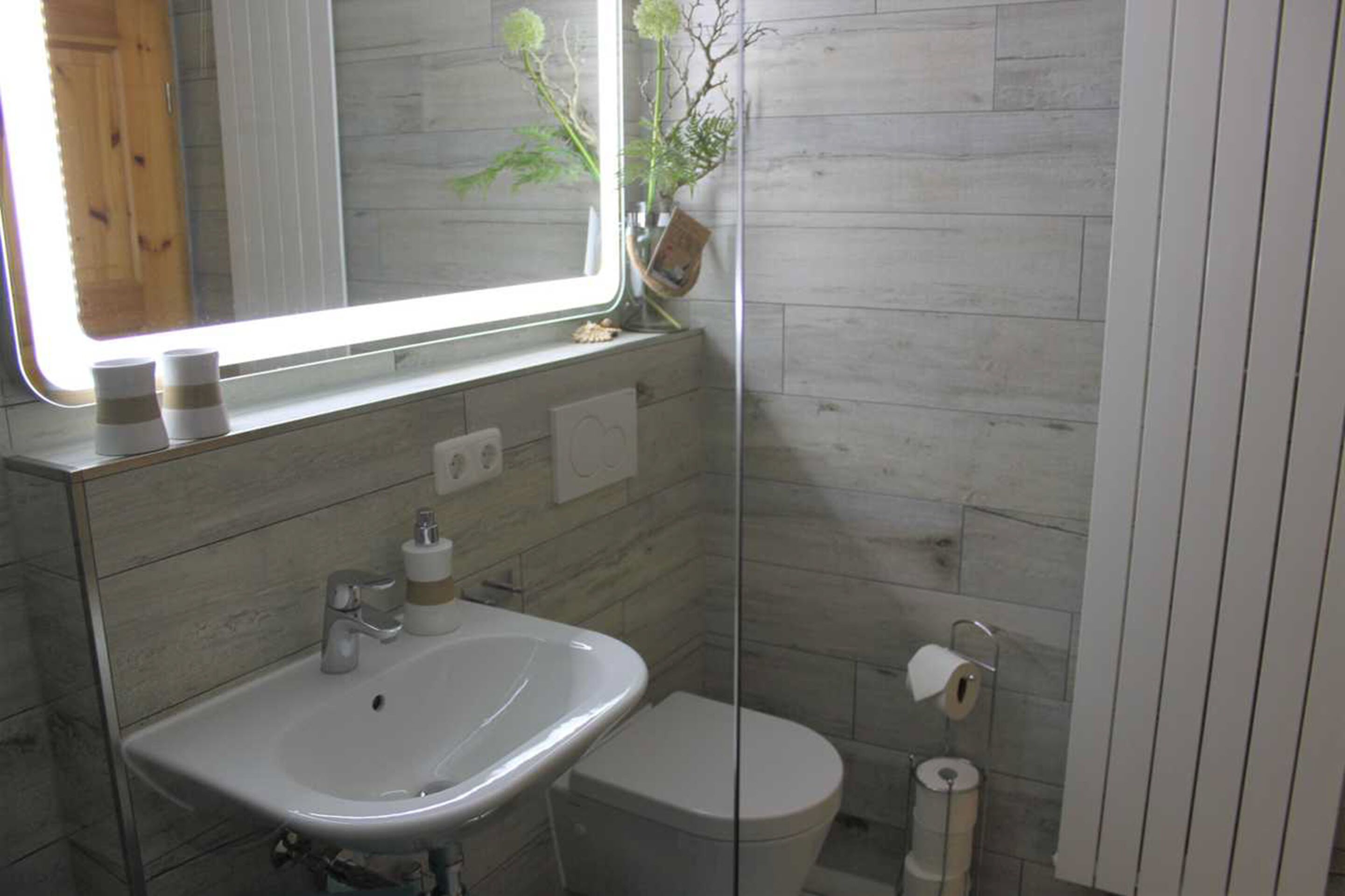 A bathroom with a white sink, a toilet, and a mirror above the sink.