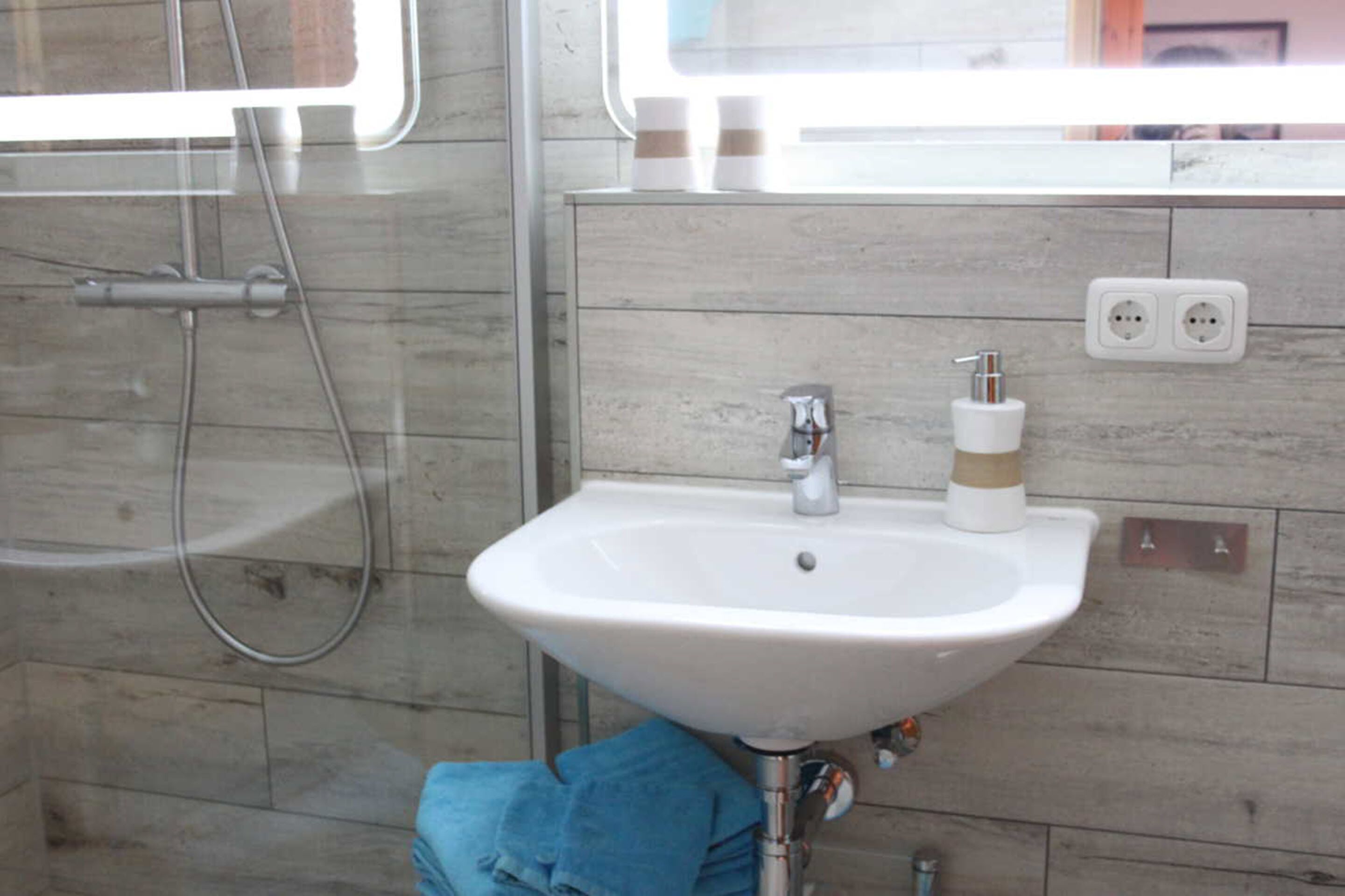 Un baño con lavamanos blanco, un espejo y un perchero para toallas.