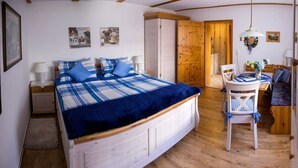 Une chambre à coucher comprenant un lit, une table de chevet, une chaise, une petite table et une porte donnant sur une autre pièce.