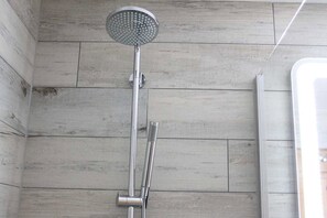 Een douche met een handdouche en een kraan aan de muur.