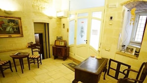A room with a wooden table, two chairs, a small cabinet, and a painting on the wall. - B&B Del Castelvecchio (Matera)