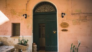 A green door with a metal grill, a small window with bars, and a stone planter with a cactus. - B&B Del Castelvecchio (Matera)