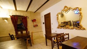 A dining area with wooden tables and chairs, a red bicycle, and a large ornate mirror on the wall. - B&B Del Castelvecchio (Matera)